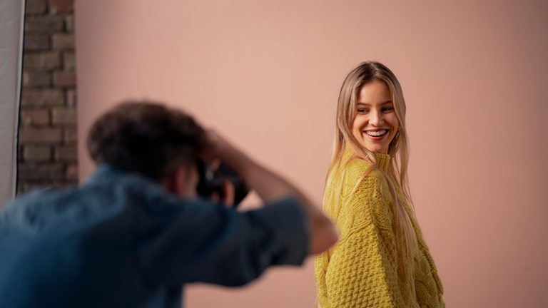 A young photographer taking picures of model, backstage of photoshooting in studio.